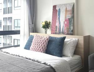 a bedroom with a bed with pillows and a window at MUXA&Vay in Pattaya North