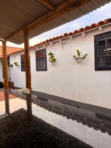 uma casa branca com duas janelas e dois vasos de plantas em Primo`s 2 Suites & Hostel em Búzios