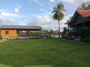 a house with a grass yard next to a building at Boune Hom Guesthouse Sunrise Don Det in Don Det