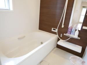 a white bathroom with a tub and a toilet at Lulumalu AMAMI in Amami