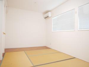an empty room with a yellow floor and two windows at Lulumalu AMAMI in Amami