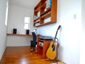 a room with a guitar and a desk with a keyboard at Lulumalu AMAMI in Amami