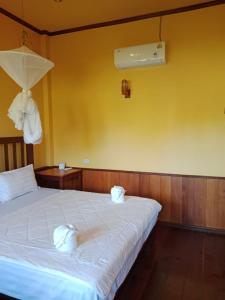 a bedroom with a bed with two towels on it at Boune Hom Guesthouse Sunrise Don Det in Don Det