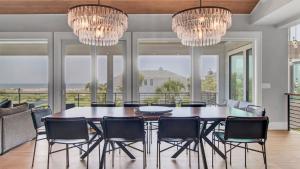 a dining room with a table and chairs and chandeliers at 3 47th Avenue by AvantStay Oceanfront Private Pool View in Isle of Palms