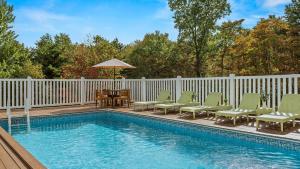 a swimming pool with chairs and a table and an umbrella at Mountain Mindset by AvantStay Pool Hot Tub Game Room Firepit in Long Pond