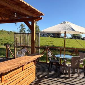 a deck with a table and chairs and an umbrella at Hostal y Domos Bello Horizonte in Villarrica