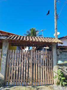 een houten hek voor een huis bij Casa Ventilada e Confortável, Perto da Rodovia e 2km da Praia in Caraguatatuba