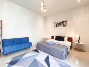 a bedroom with a bed and a blue couch at The Lavana Rumah Keboon in Mataram