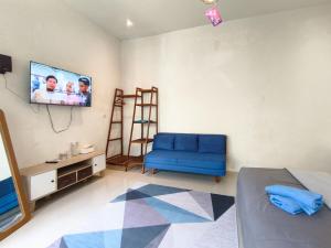 a living room with a blue chair and a flat screen tv at The Lavana Rumah Keboon in Mataram