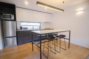 a kitchen with a counter with stools and a refrigerator at Lakes Edge 4 in Wendouree