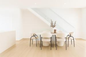 una sala da pranzo bianca con tavolo e sgabelli di Rochedale Outlook a Rochedale