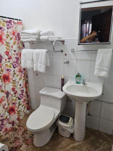 a bathroom with a white toilet and a sink at El hostal de Uriel in Izalco