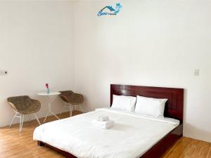 a bedroom with a bed with white sheets and two chairs at Ben's House 2 in Tam Ky