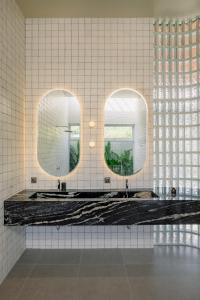 a bathroom with two sinks and two mirrors at The Outside Design Suites in Uluwatu +32 photos