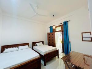 a bedroom with two beds and a table at Blue Heaven Main in Wellawaya