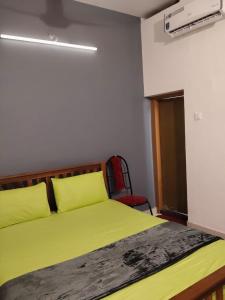 コーラムにあるSunny's Holiday Homesのベッドルーム(黄色のベッド1台、赤い椅子付)
