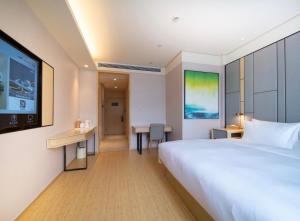 a hotel room with a bed and a flat screen tv at JI Hotel Hangzhou Banshan Road in Hangzhou