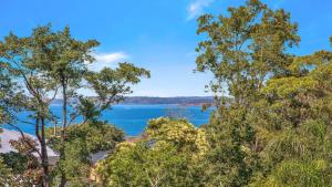 a view of a body of water through trees at 'Spacious Family Retreat' by HolidayCo in Killcare +16 photos