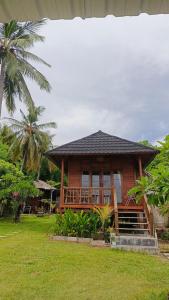a wooden house with a porch in the grass at Yellow Coco Gili Gede in Gili Gede