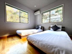 two beds in a room with two windows at Villa MAEUMー熱海絶景の棟貸しヴィラ BBQとペレットストーブ体験 最大13名追加料金なし in Atami