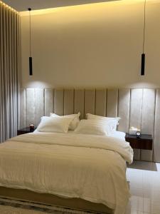 a bedroom with a large bed with white sheets and pillows at شقة بغرفة معيشة وغرفة نوم in Buraydah
