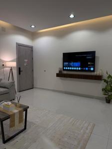 a living room with a couch and a tv on a wall at شقة بغرفة معيشة وغرفة نوم in Buraydah