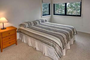 a bed in a bedroom with a nightstand and two windows at Delmonte in Medlow Bath
