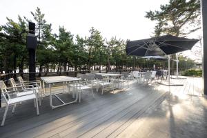 um deque com mesas e cadeiras e um guarda-sol em Hotel Hound Gangneung Gyeongpo em Gangneung