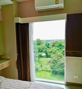 a bedroom with a window with a view of a forest at The new concept office plus in Ban Fon