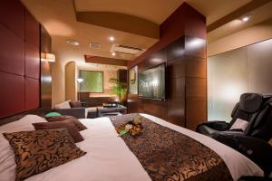 a hotel room with a large bed and a chair at HOTEL SULATA Sapporo (Adult Only) in Sapporo