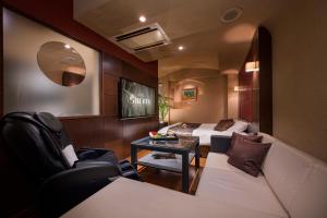 a room with a couch and a bed and a table at HOTEL SULATA Sapporo (Adult Only) in Sapporo