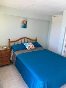 a bedroom with a blue bed and a night stand at Superstar Living in Treasure Beach