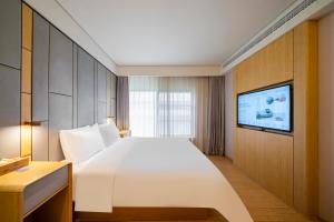 ein Hotelzimmer mit einem großen Bett und einem Fernseher in der Unterkunft JI Hotel Shanghai Wujiaochang Wanda Plaza in Shanghai