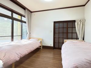 two beds in a room with a window at 一棟貸しの宿 貸別荘 水戸ハウス Vacation Rental Mito House! Location is 1-2-55 Kanemachi Ibaraki Prefecture 場所は茨城県水戸市金町1-2-55です ドア横のキーボックスの番号はご予約後に,チェックイン情報を見る,をご覧下さい in Mito