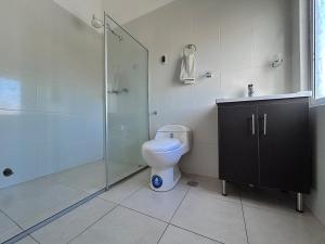 a bathroom with a toilet and a glass shower at Corta Estadía Sucre in Sucre +7 photos
