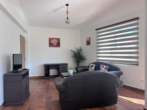 a living room with a black couch and a television at Corta Estadía Sucre in Sucre