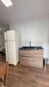a kitchen with a white refrigerator and a table at Flat aconchegante a 500m do centro de Chapecó in Chapecó