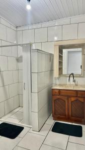 a white tiled bathroom with a sink and a shower at Flat aconchegante a 500m do centro de Chapecó in Chapecó