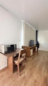 a living room with a table and a microwave at Flat aconchegante a 500m do centro de Chapecó in Chapecó