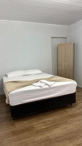 a large bed in a bedroom with a wooden floor at Flat aconchegante a 500m do centro de Chapecó in Chapecó