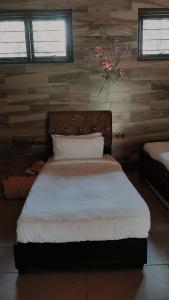 Teratak Jannah Homestay & Resort في كوالا لكانغسار: غرفة نوم بسرير أبيض وجدار خشبي