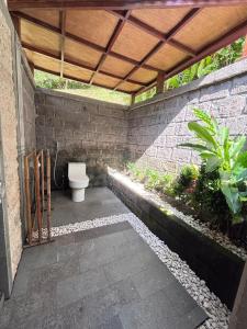 Balian River Hut في Balian: حمام مع مرحاض تحت سقف خشبي