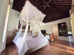 a bedroom with a canopy bed with mosquito net at Balian River Hut in Balian +7 photos
