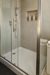 a shower with a glass door in a bathroom at Spacious Modern 5 bedroom home near Heathrow Windsor in Canvey +28 photos