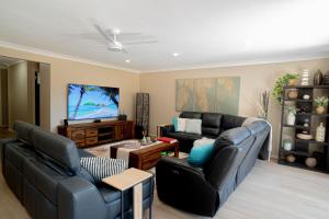 a living room with black leather furniture and a flat screen tv at Luxury at Lagoon Estate in Nelson Bay