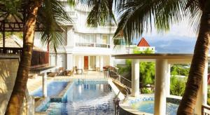 Hotel Minahasa في مانادو: فندق مع مسبح وأشجار نخيل