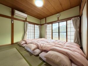 a large bed in a room with windows at 一棟貸しの宿 貸別荘 水戸ハウス Vacation Rental Mito House! Location is 1-2-55 Kanemachi Ibaraki Prefecture 場所は茨城県水戸市金町1-2-55です ドア横のキーボックスの番号はご予約後に,チェックイン情報を見る,をご覧下さい in Mito