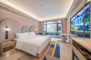 a bedroom with a large white bed and a large window at 长白山 Mercure Hotel in Baomacheng