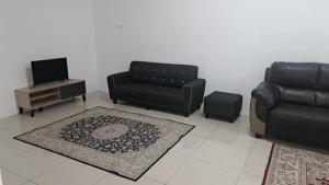 a living room with a couch and a chair and a table at Sakeena Homestay in Padang Serai
