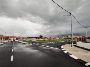 an empty street in a town with a cloudy sky at Sakeena Homestay in Padang Serai